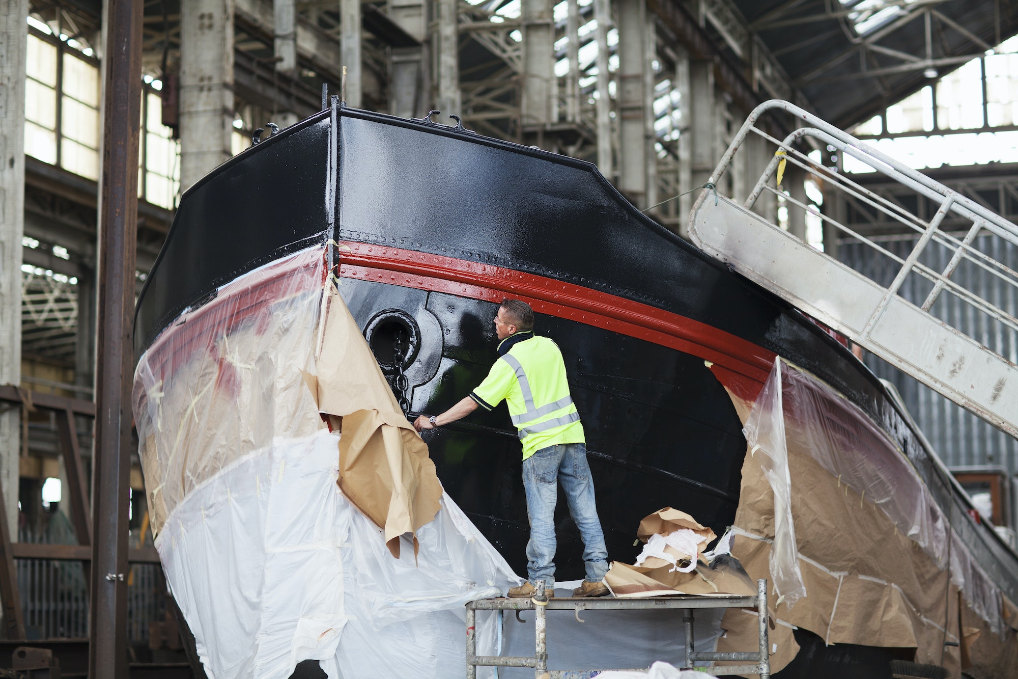 Workers unwrapping boat in shipyard